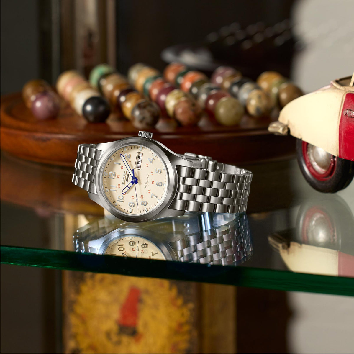 Seiko 5 Sports SRPK41K1 stainless steel bracelet resting on a glass shelf reflection view