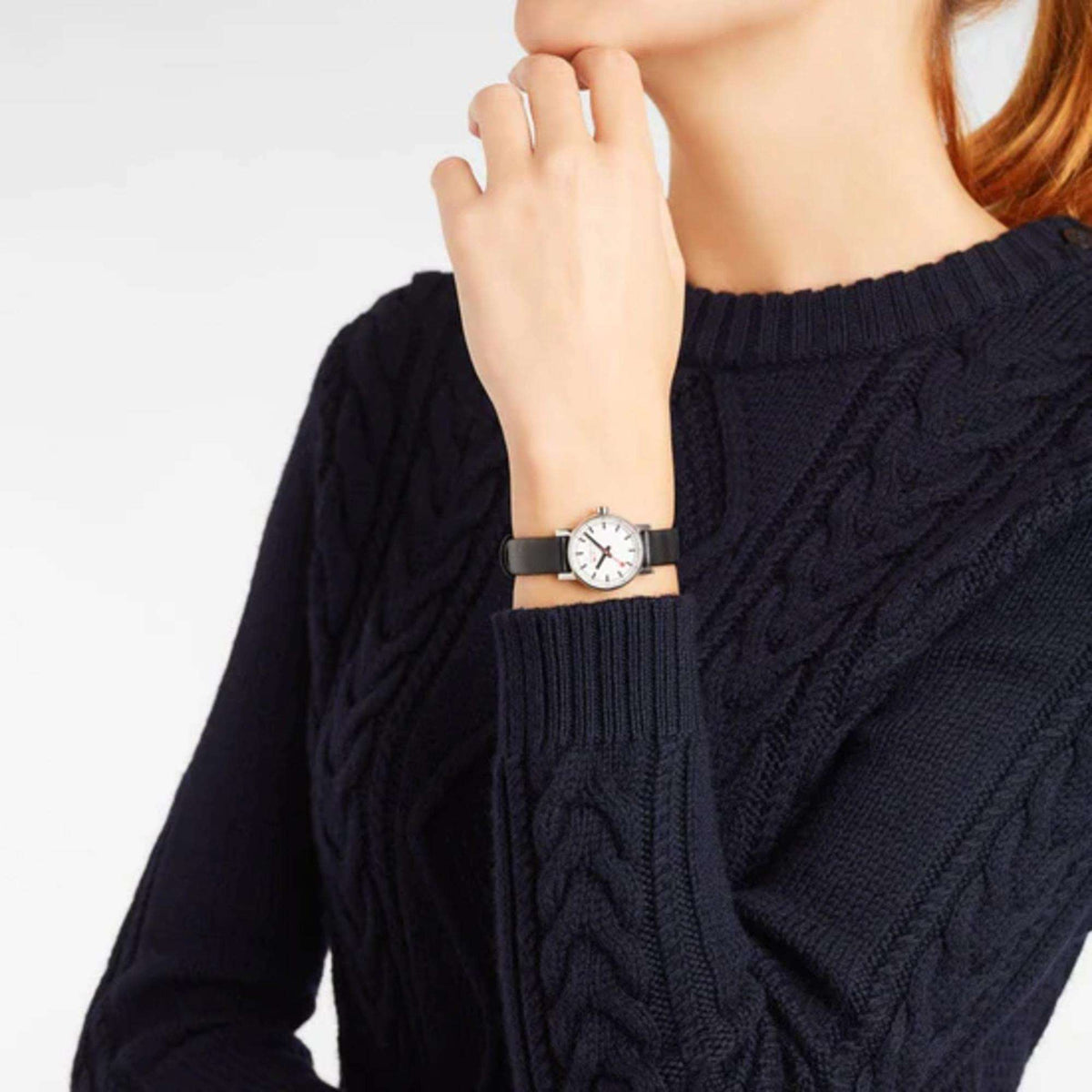 Mondaine ladies watch on wrist, black leather strap and white dial with red seconds hand