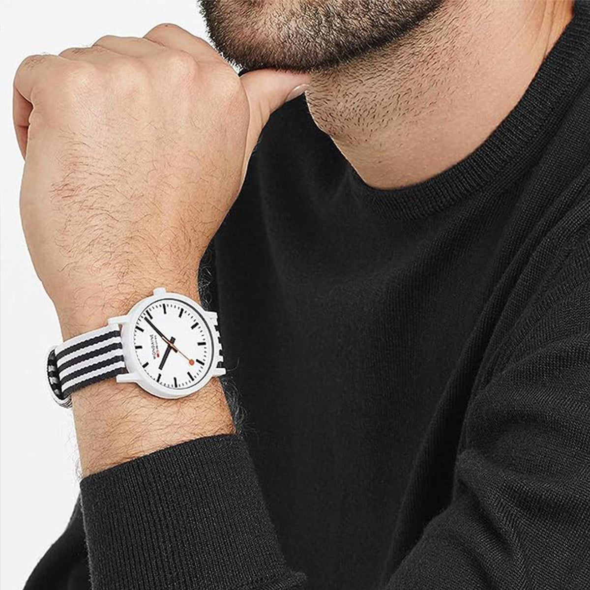 Mondaine watch on wrist, white dial and red hands, black striped fabric strap