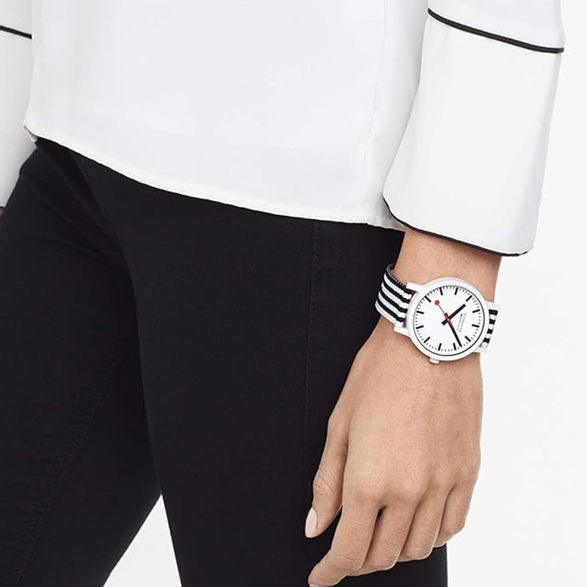 Mondaine watch on wrist, round white dial with red second hand, black-and-white striped band
