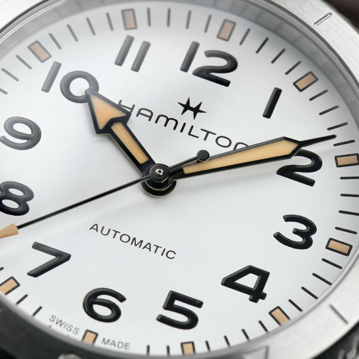 Close-up of white dial with Arabic numerals, black hands, and yellow accents