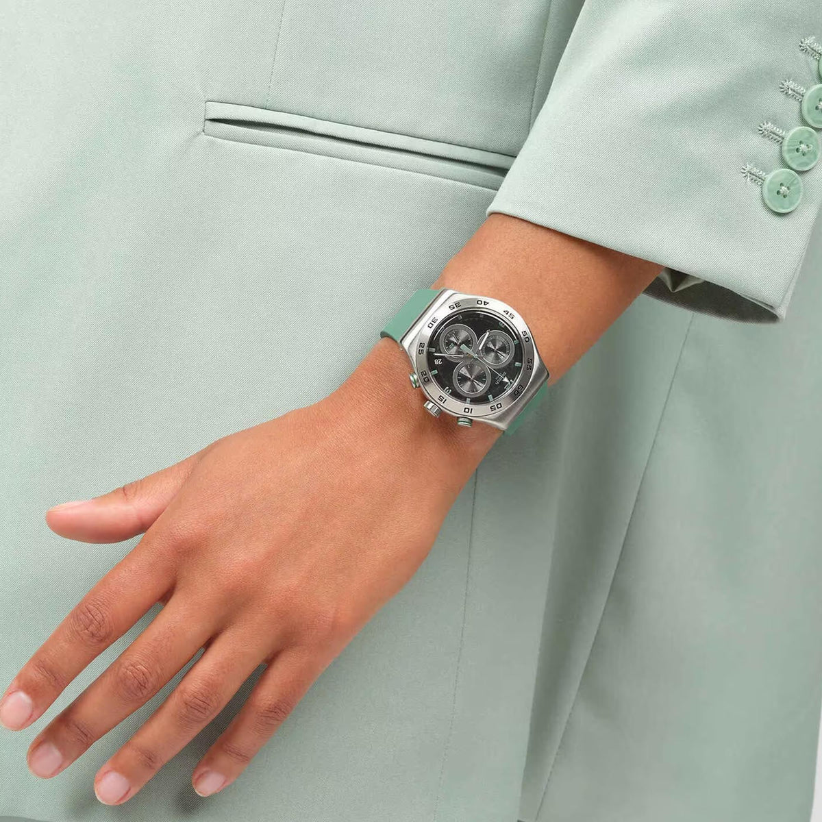 Green silicone strap multi-dial watch on wrist with silver case and black dial with green markers.