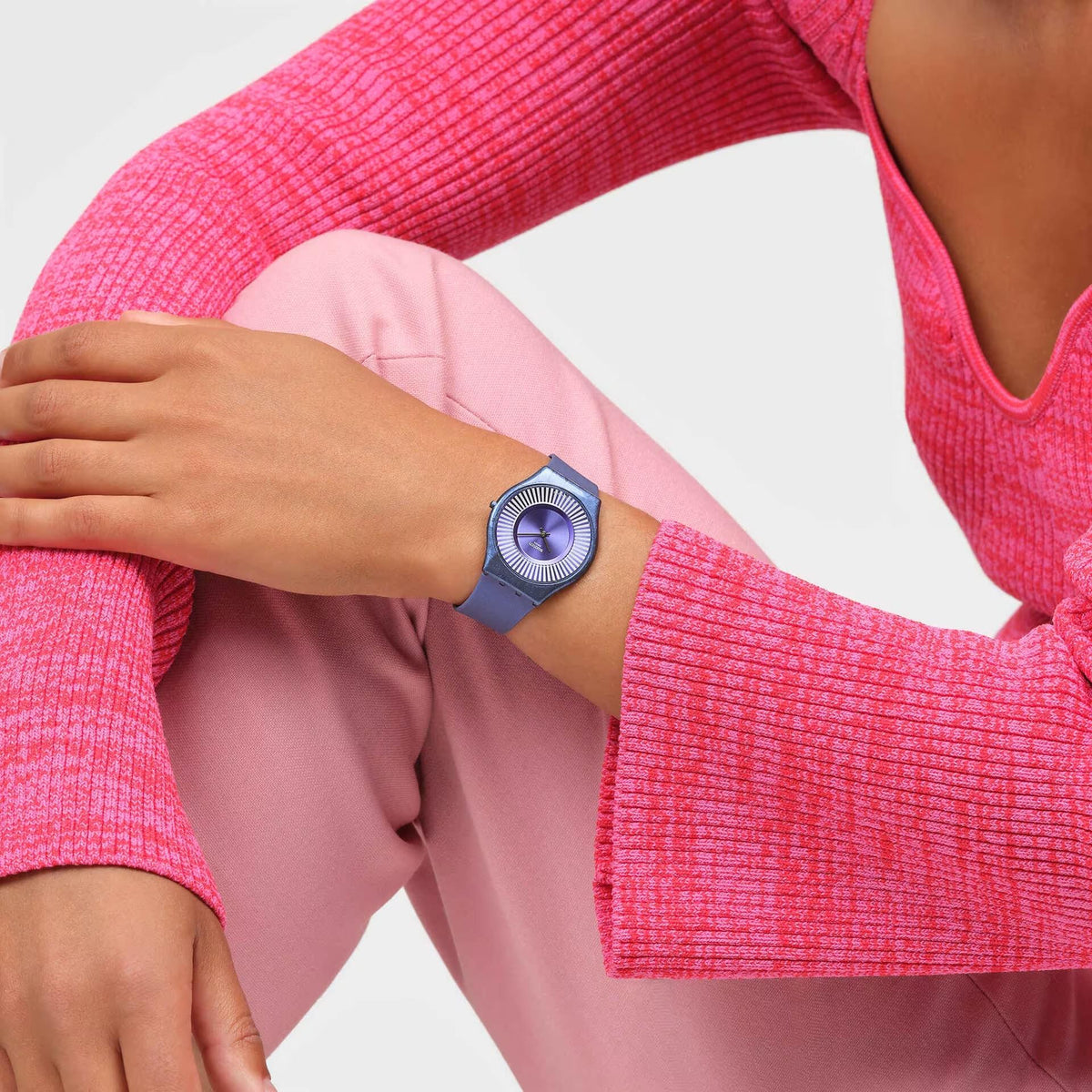 Blue silicone Swatch watch on wrist, blue dial with striped bezel