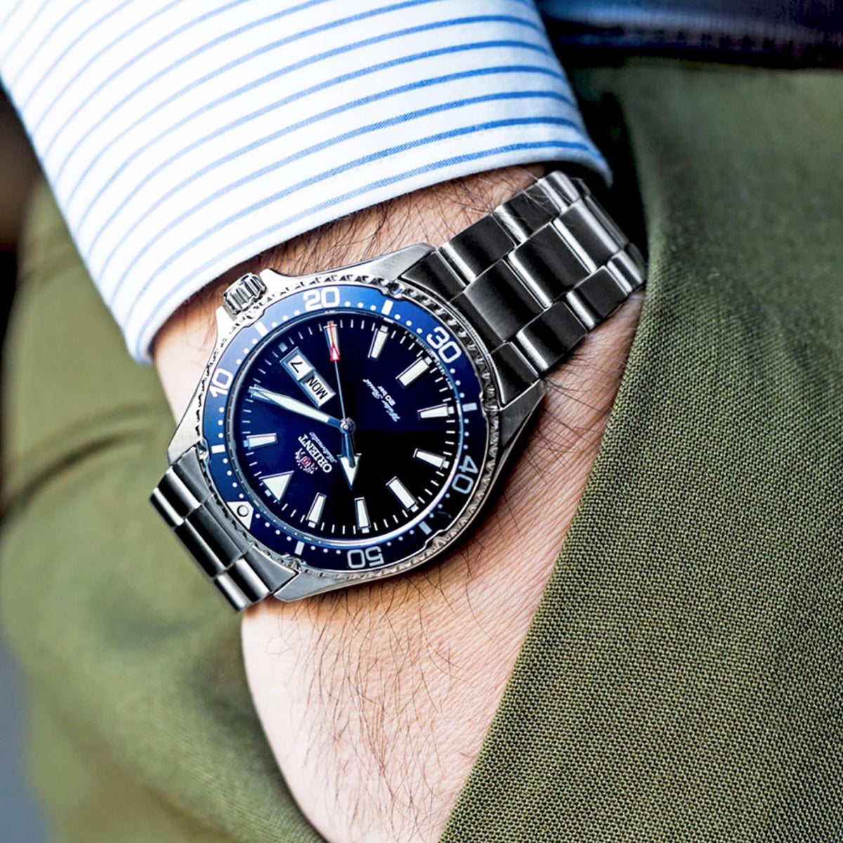 Men's automatic wristwatch on wrist, blue dial and steel bracelet with date window