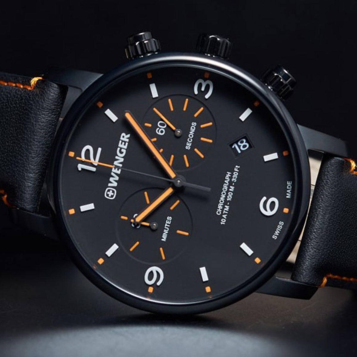Wenger chronograph watch face with orange markers, black dial, and date at 18
