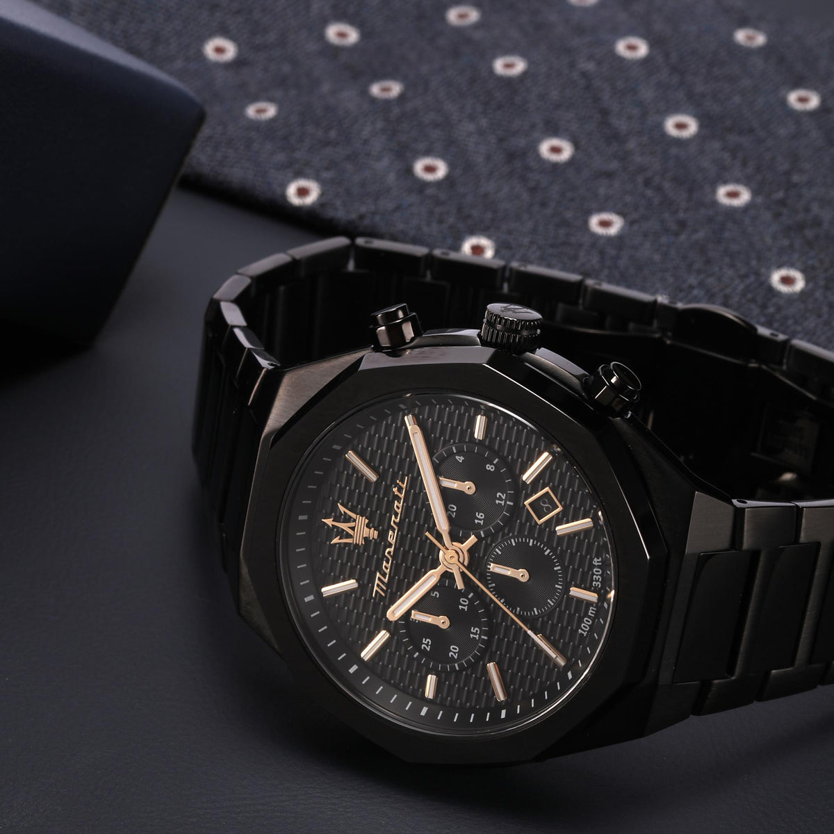 Black chronograph watch with gold-tone hands and multiple subdials on black steel bracelet.