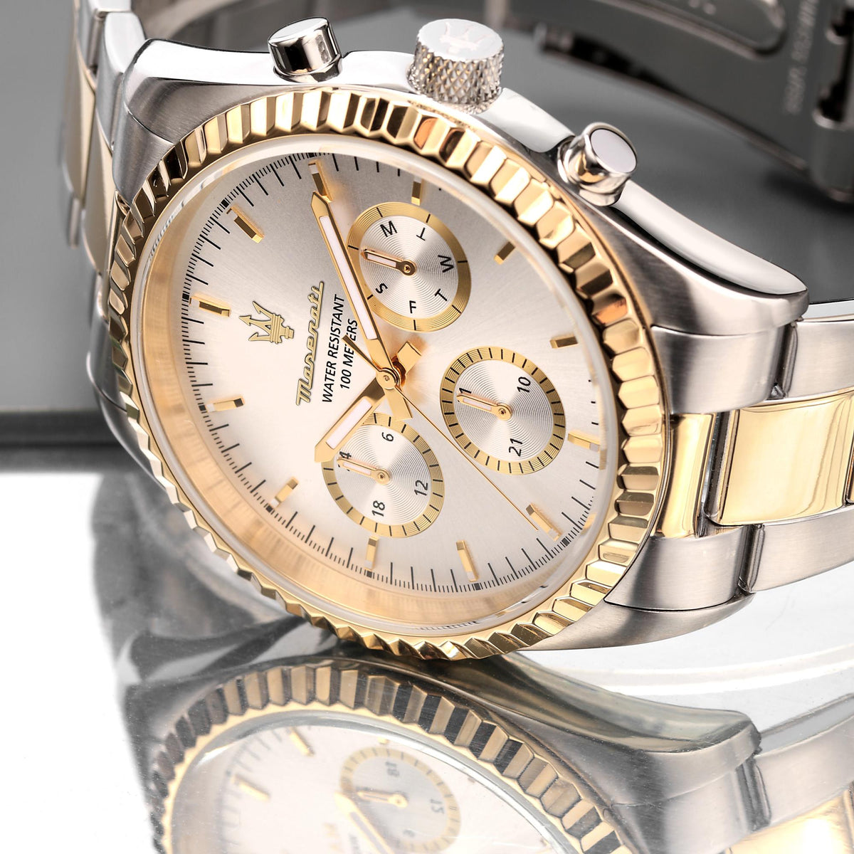 Close-up of two-tone steel chronograph watch with silver dial, gold bezel, and crown