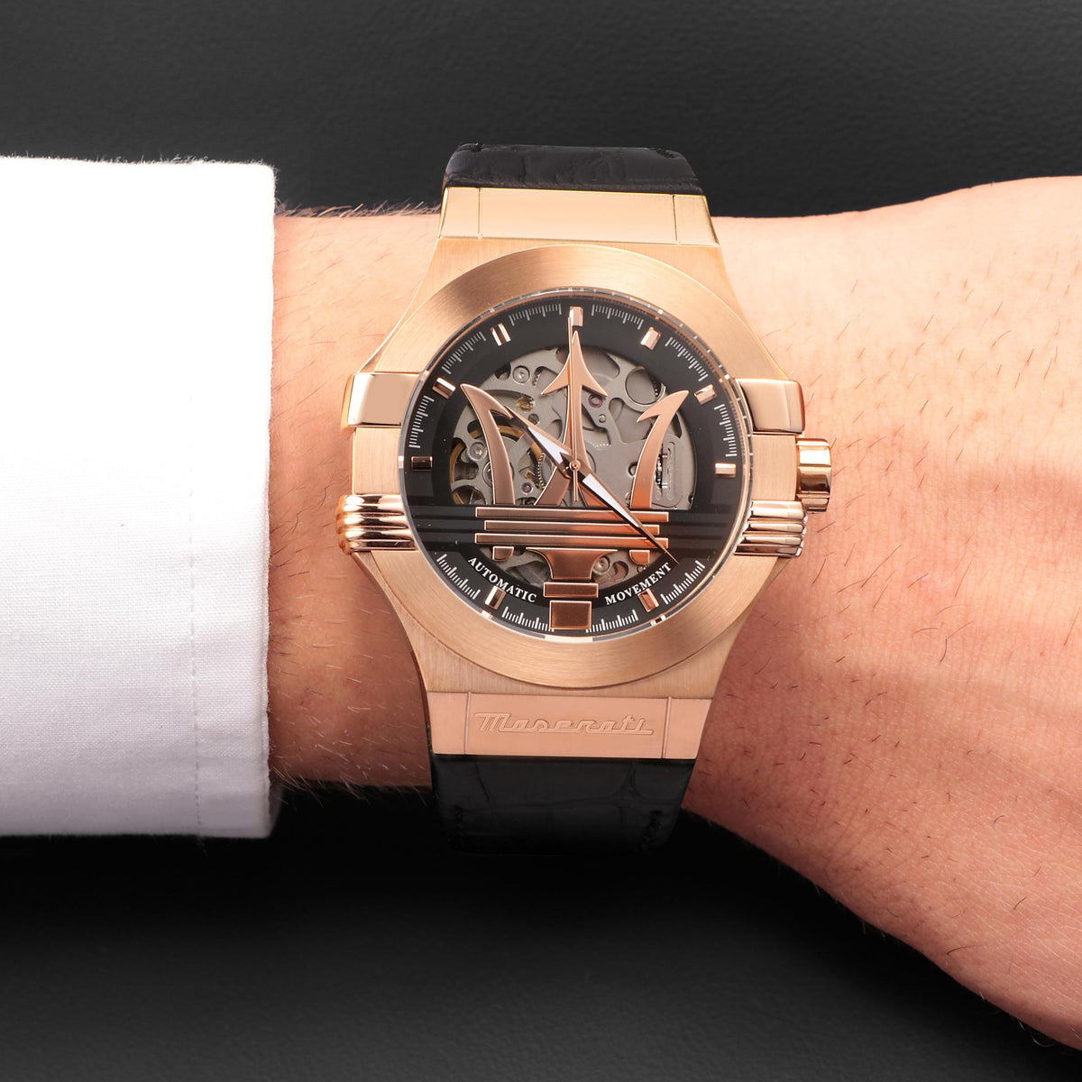 Men's skeleton watch on wrist with black dial and black leather strap, rose gold-tone bezel.
