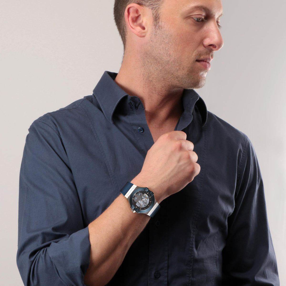 Men's wristwatch with blue strap and skeleton dial, worn with a dark blue shirt