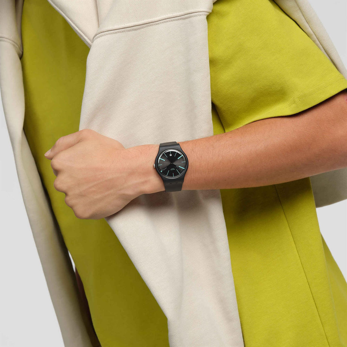 Swatch unisex watch on wrist, black dial and black silicone strap with mint-green accents.