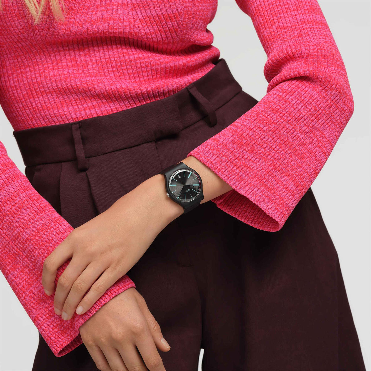Swatch unisex watch on wrist, black dial with mint-green hands, black silicone strap.