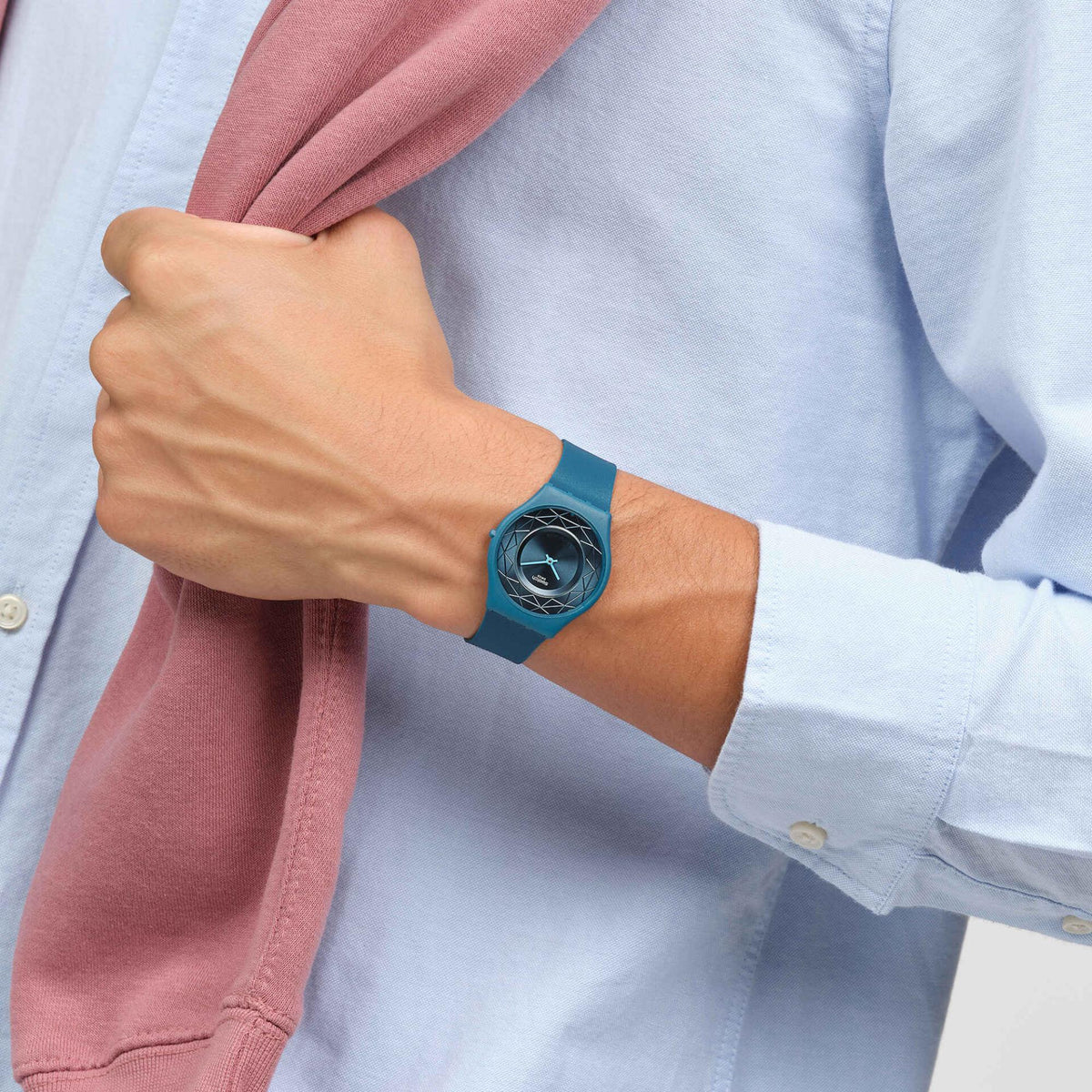 Unisex teal silicone strap watch on wrist, round geometric dial with Swatch logo
