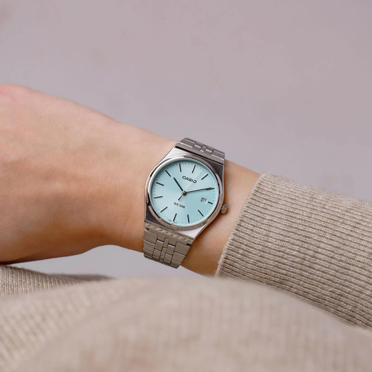 Casio quartz watch on wrist with light blue dial and stainless steel bracelet in sweater