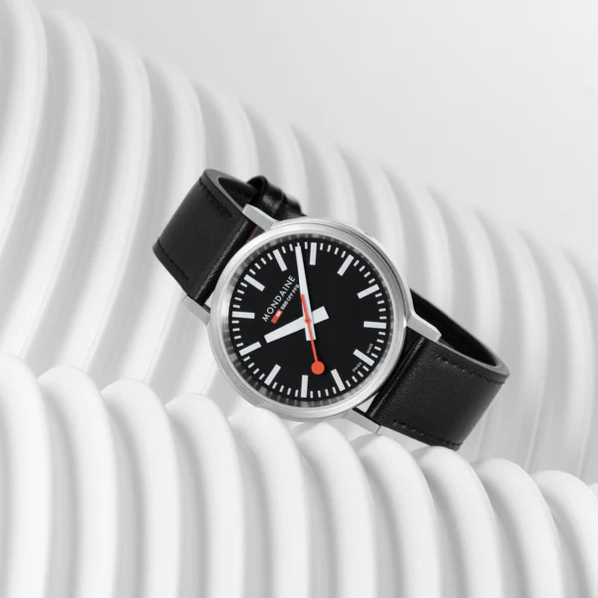 Mondaine stop2go quartz watch angled view, black dial with orange seconds hand, black strap