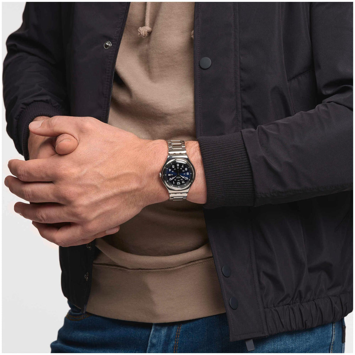 Stainless steel men's quartz wristwatch with blue dial on wrist, metal bracelet visible