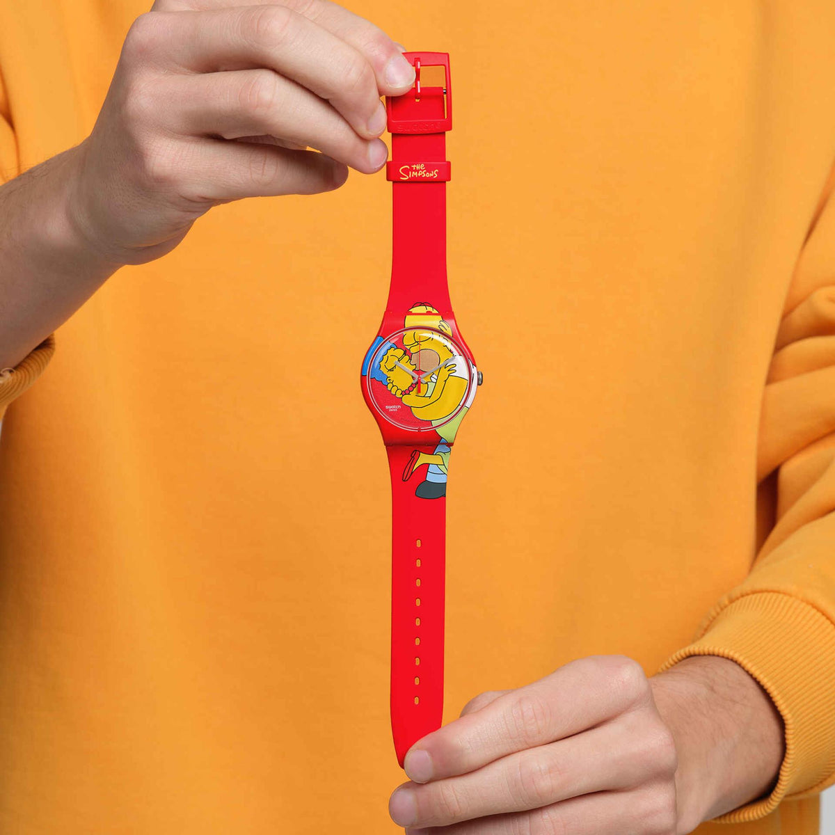 Red silicone Swatch watch with cartoon dial, held upright by clasp