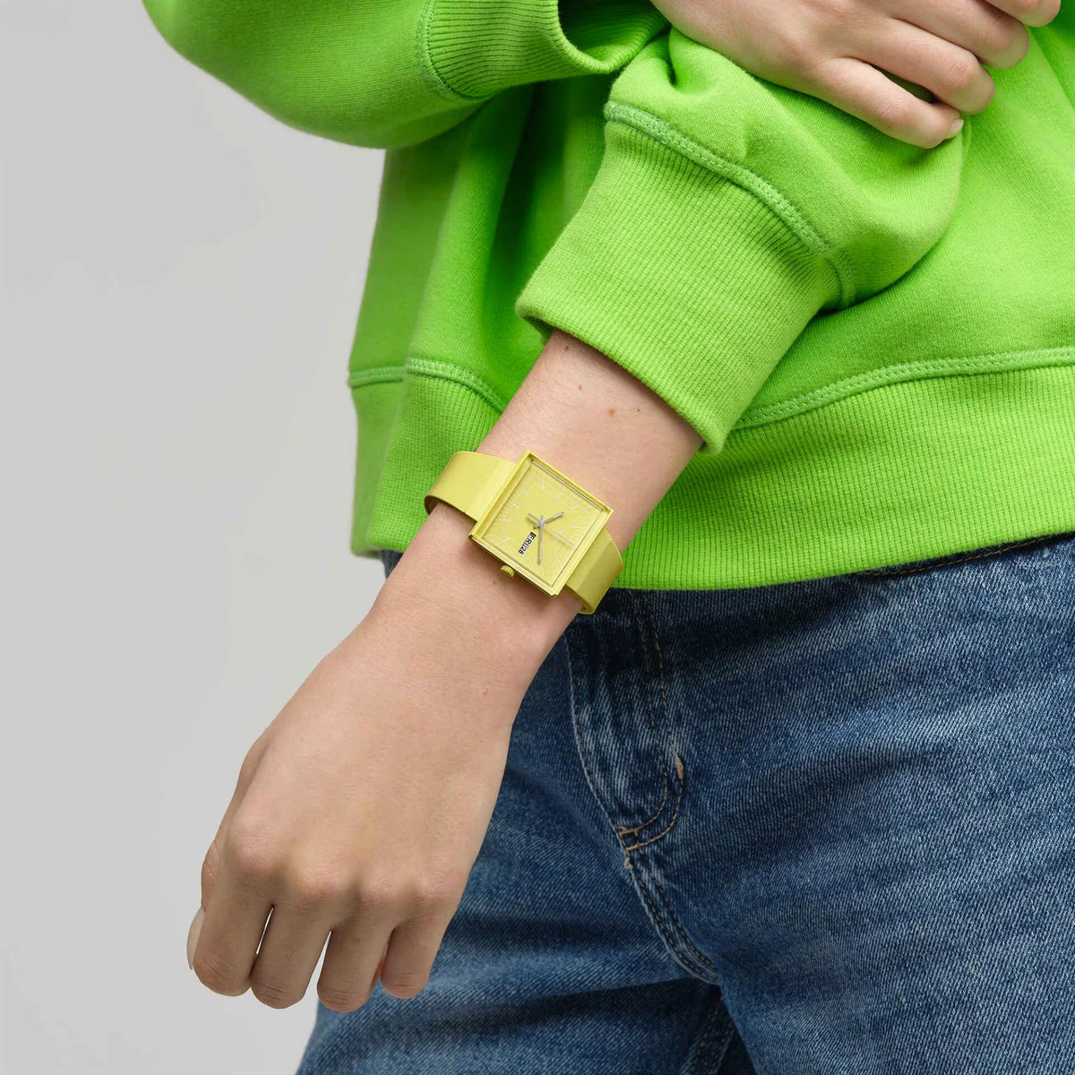 Swatch WHAT IF…LEMON? SO34J700 unisex watch on a persons wrist with green sweatshirt