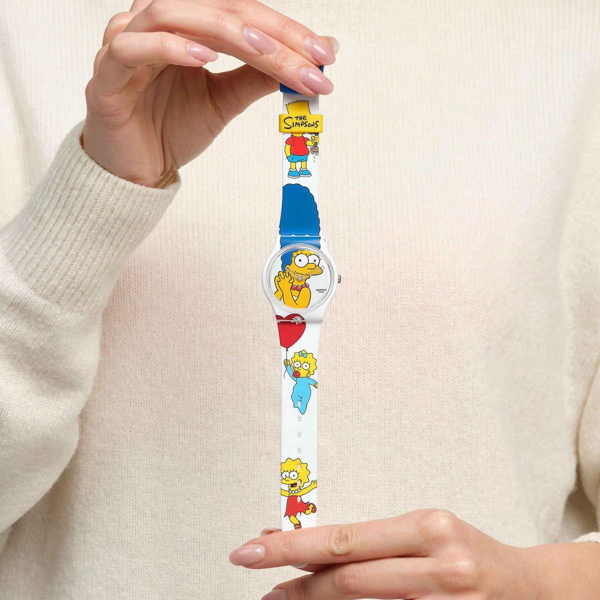 Person wearing Swatch ladies watch with white strap and repeating Simpsons character graphics