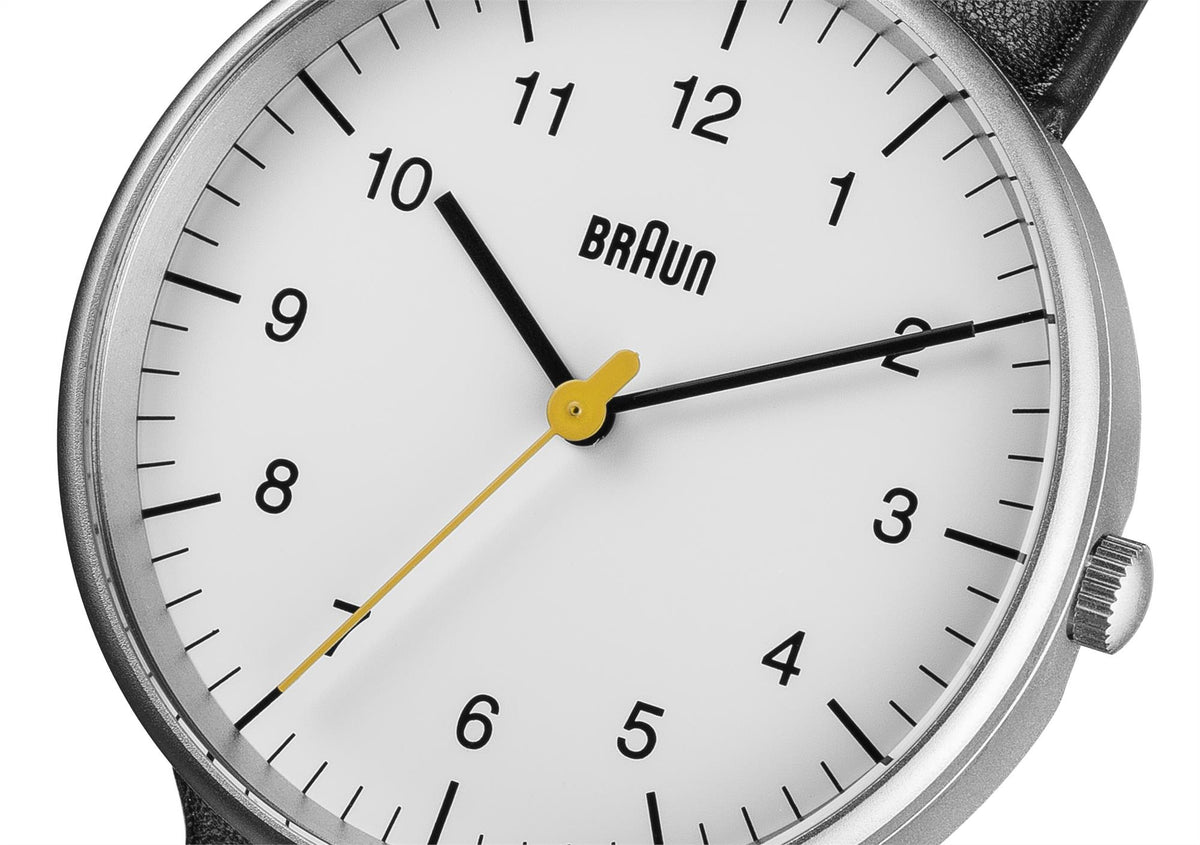 Close-up of men's watch face with white dial, black hands, and yellow second hand.