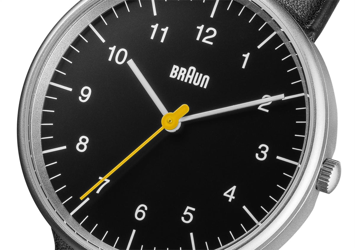 Braun quartz watch dial close-up, black face with yellow second hand and silver markers