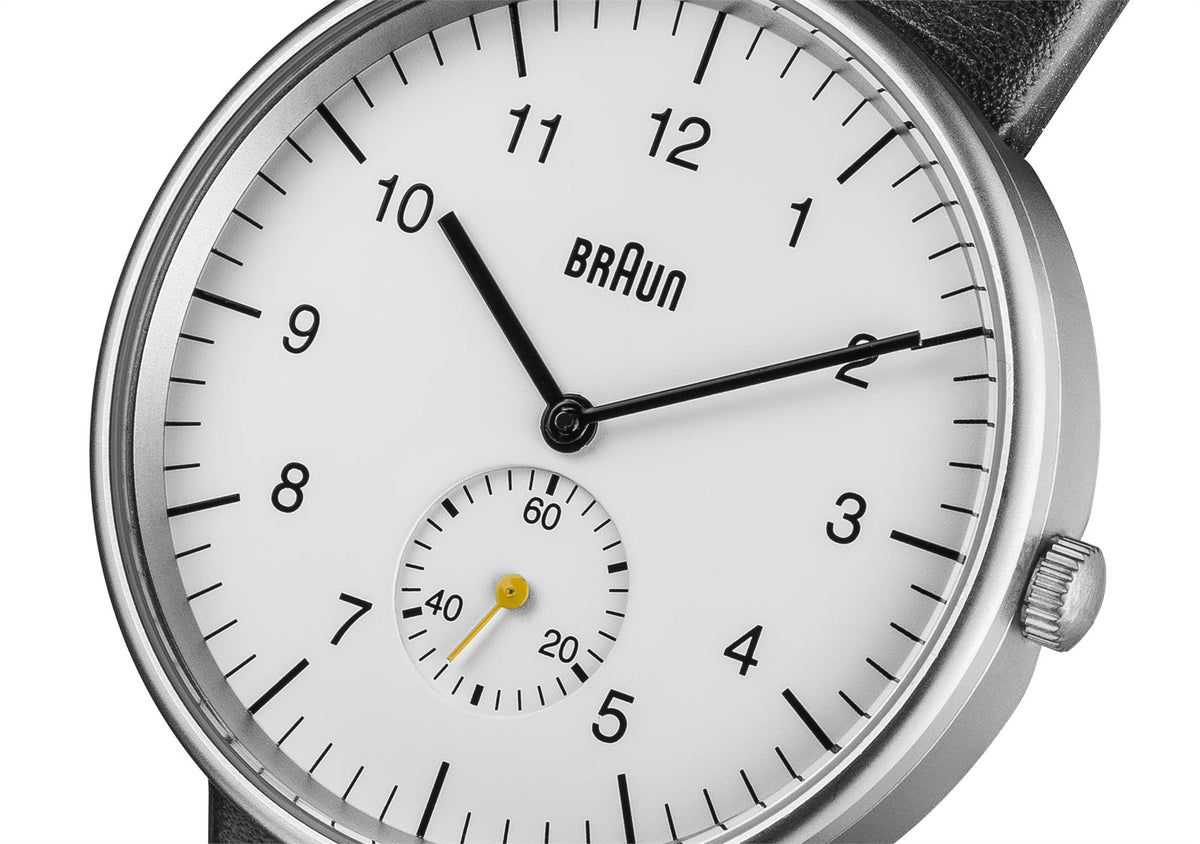 Round watch dial close-up: white face with black hands, BRAUN logo, date subdial