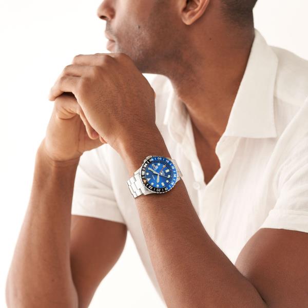 Men's steel quartz watch with blue dial worn on wrist, blue bezel visible