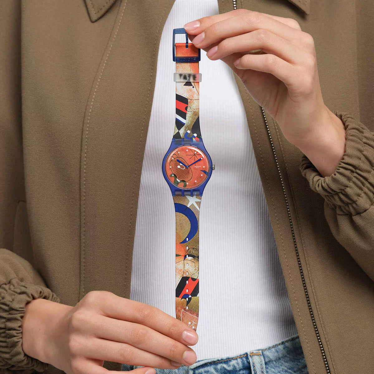 Blue silicone strap watch on wrist with orange dial and patterned band