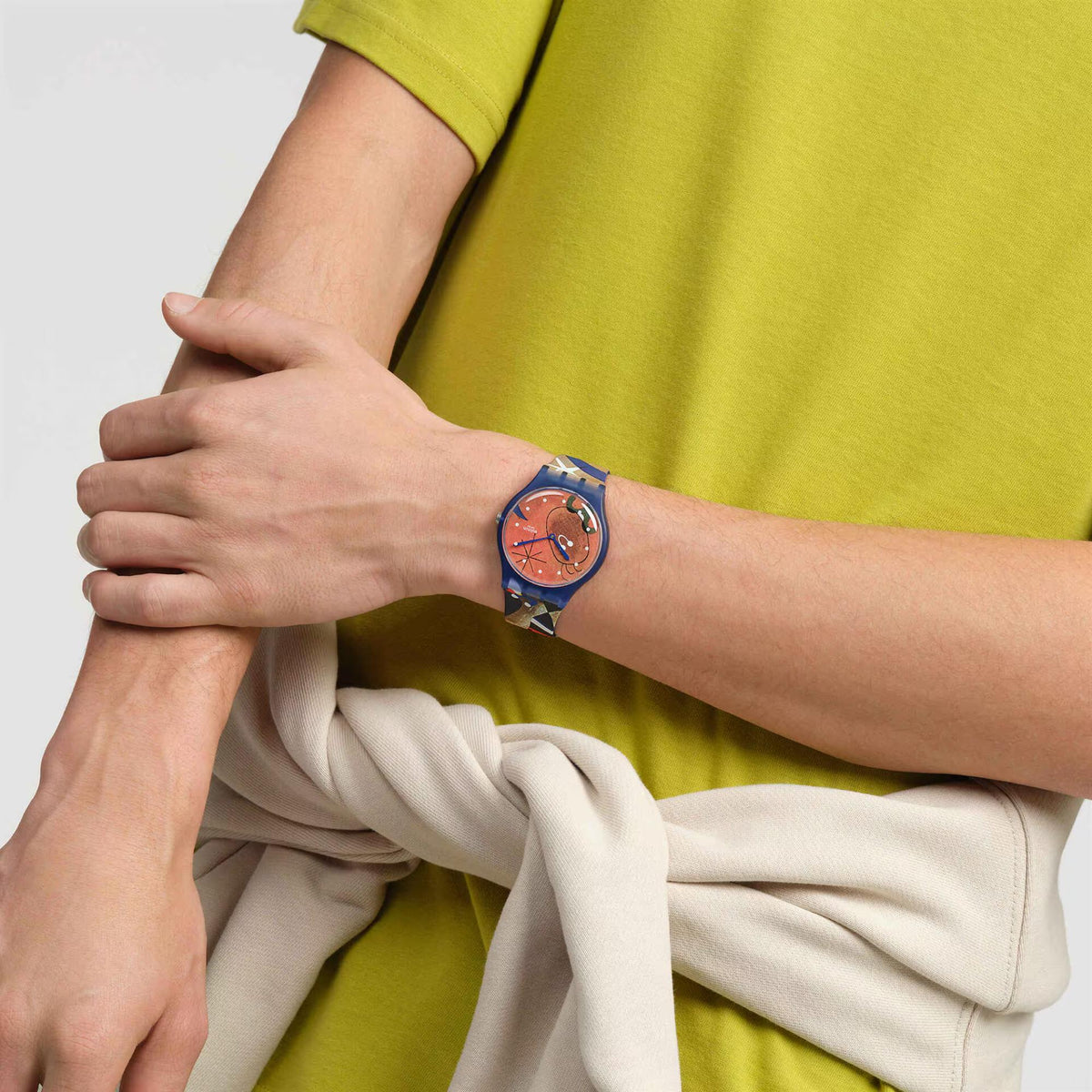 Blue silicone strap watch on wrist with orange dial and night-themed artwork