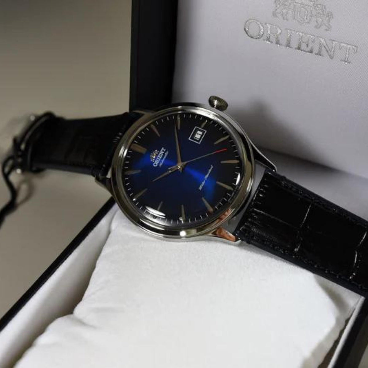 Men's automatic watch angled view: blue dial, stainless case, black leather strap, date