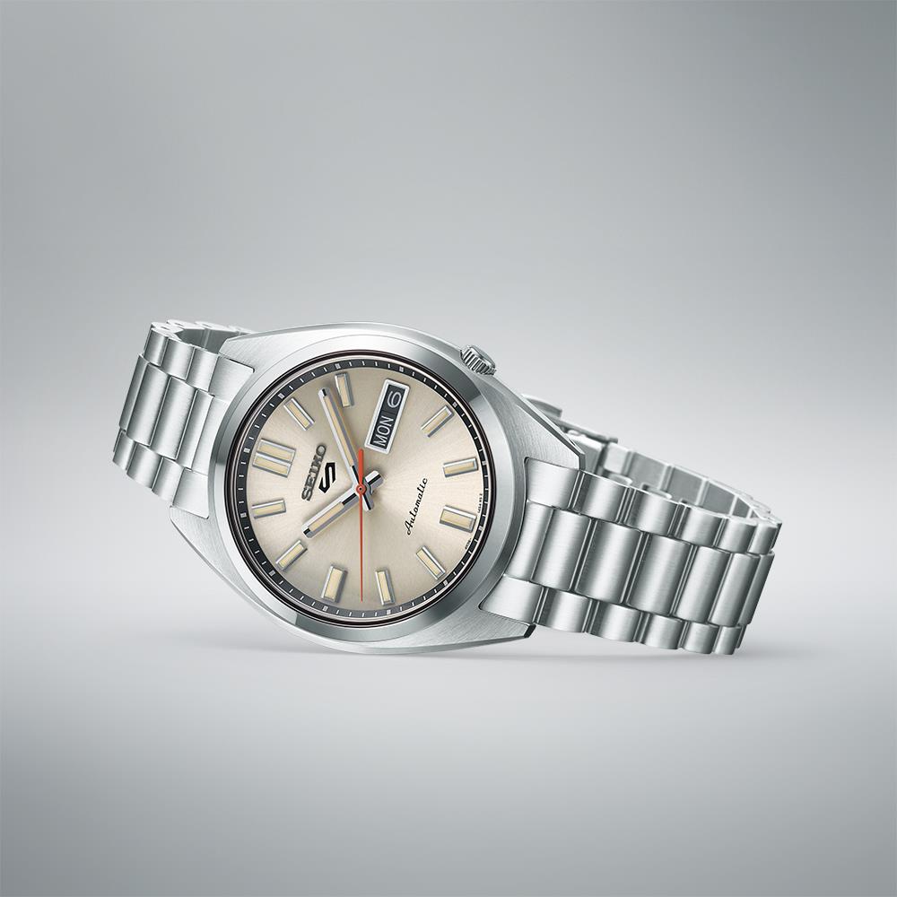 Seiko 5 Sports SNXS Classic watch with stainless steel bracelet on a gray background