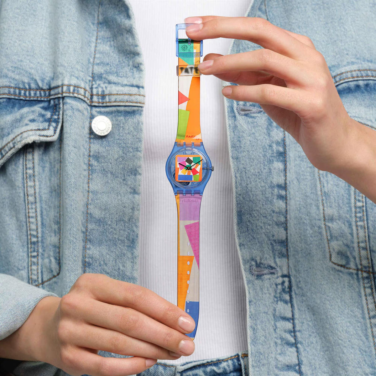 Swatch wristwatch on wrist with colorful geometric dial and clear printed strap