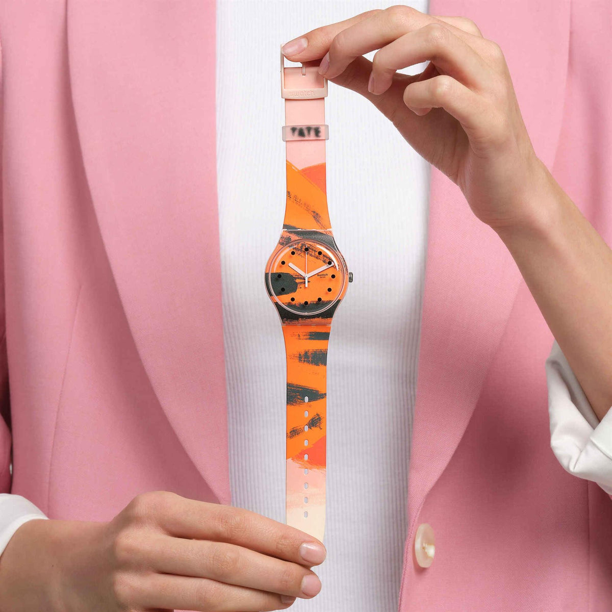 Pink silicone strap watch with orange dial, worn and held by the strap