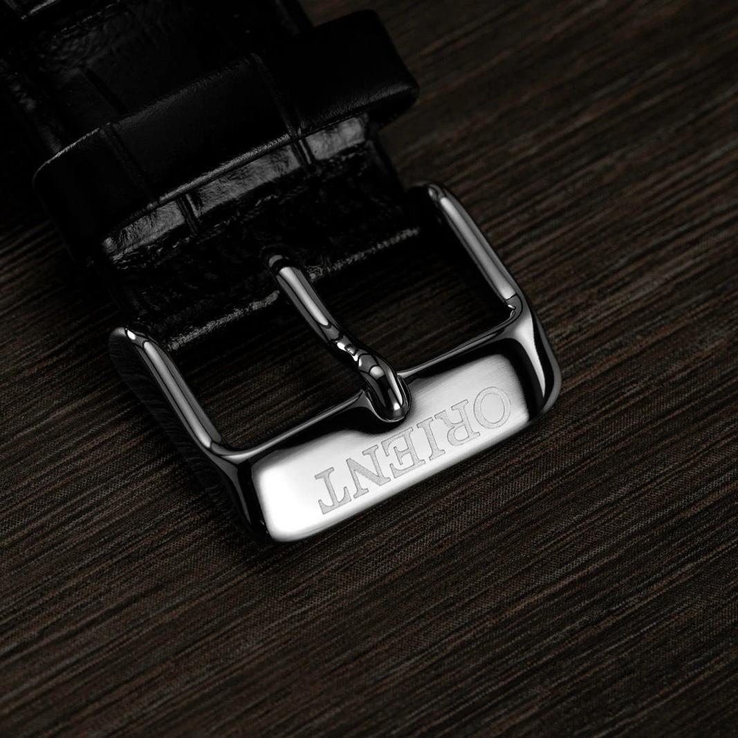 Black leather watch strap with metal buckle and engraved branding on strap end