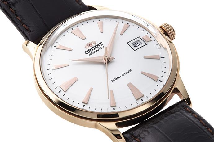Men's automatic watch close-up: white dial, rose-gold bezel, black leather strap, date window