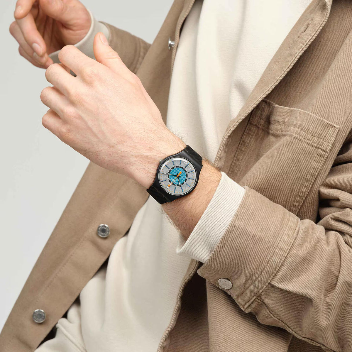 Swatch bioceramic wristwatch on wrist with black silicone strap and white dial with blue details.