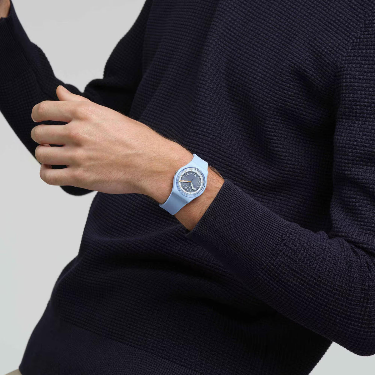 Light blue silicone watch on wrist, dark dial with orange hands and markers