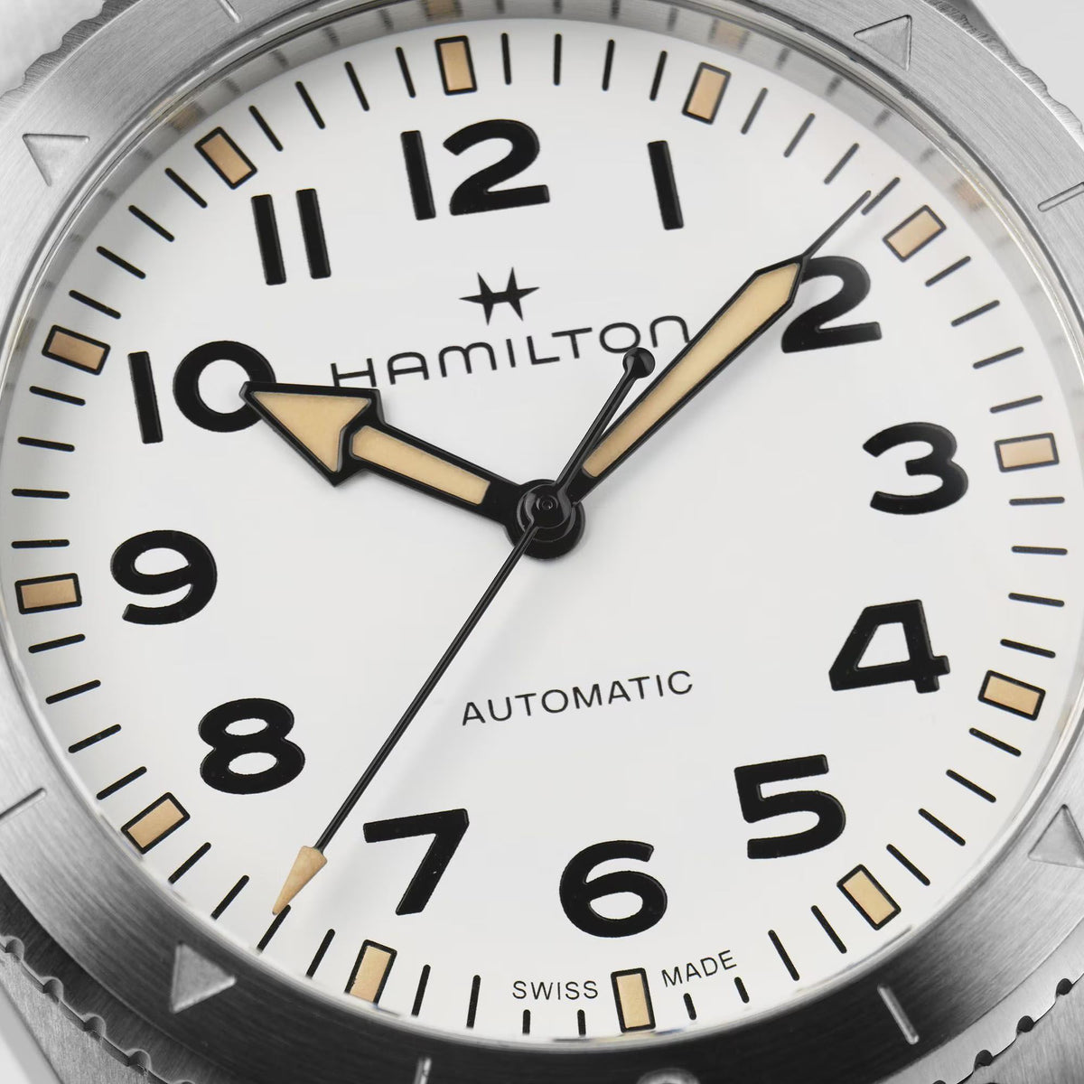 Close-up of white dial with black numerals, gold hands, and Automatic text