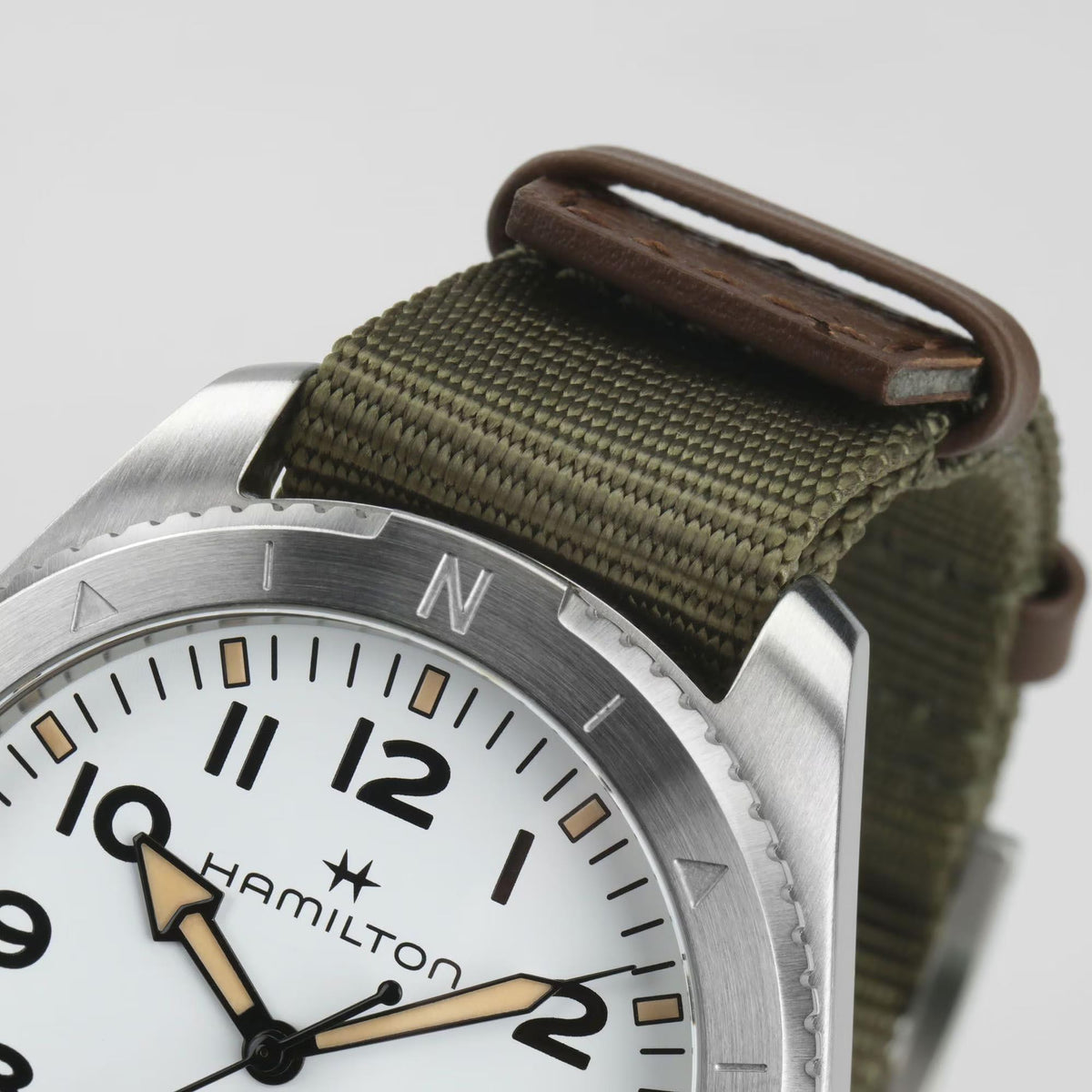 Stainless case bezel detail with N marking; khaki NATO strap and brown keeper