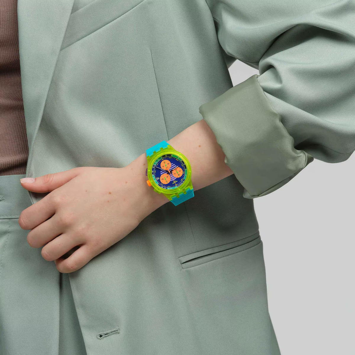 Chronograph watch on wrist with turquoise silicone strap and multicolor circular dial