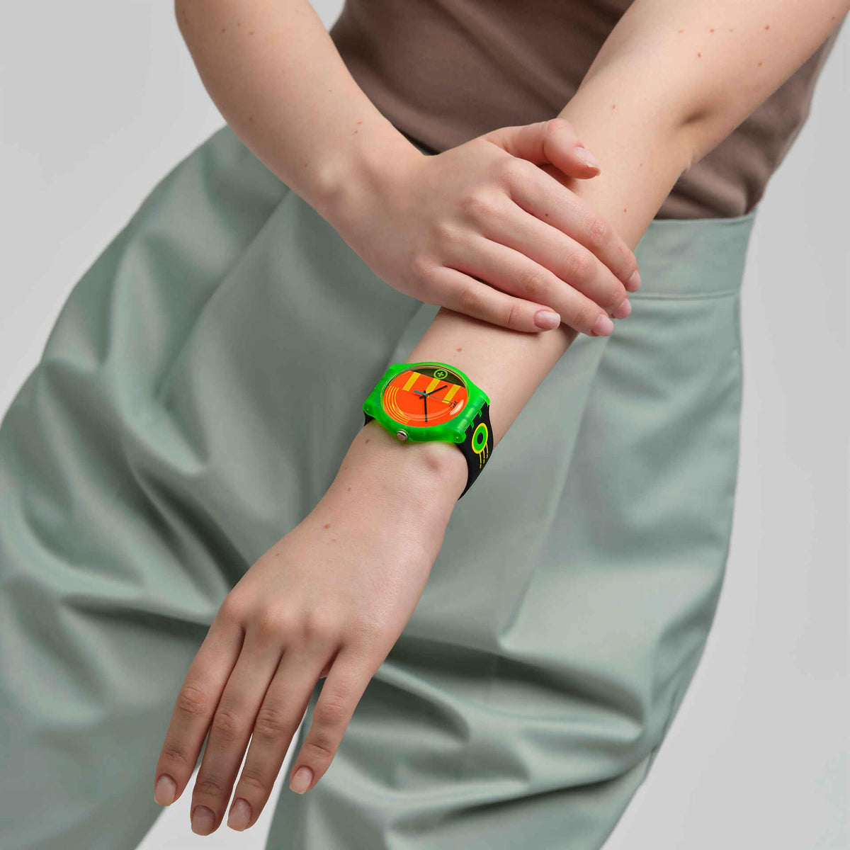 Watch on wrist with neon orange multicolour dial and black silicone strap