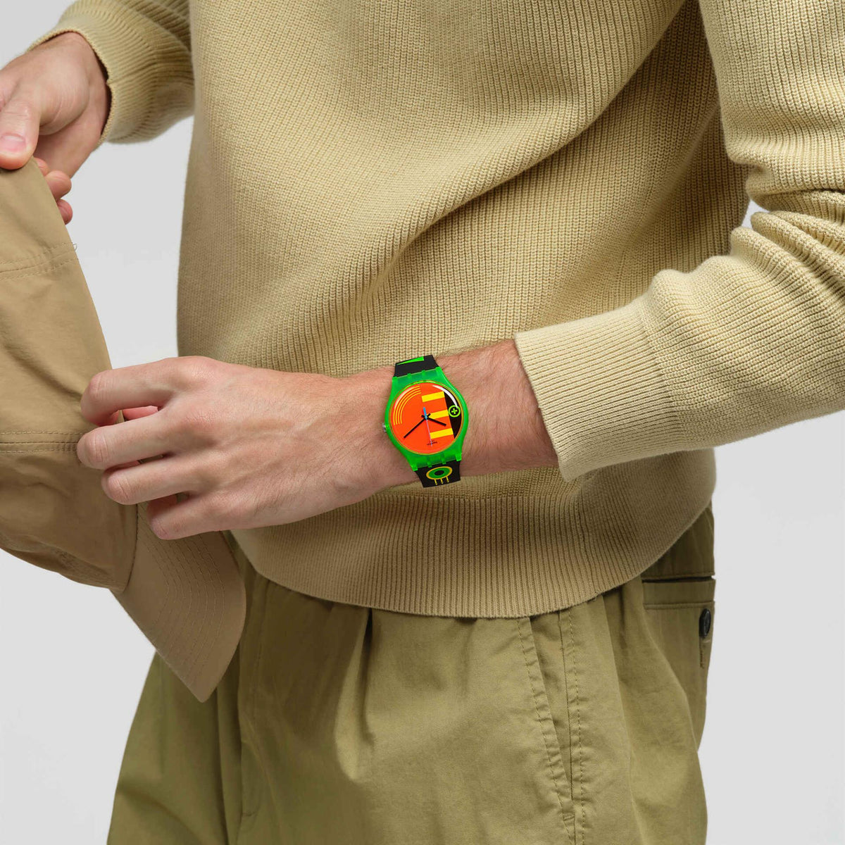 Watch worn on arm with neon orange dial and black silicone strap