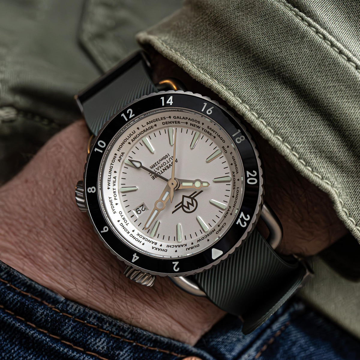 Men's watch on wrist with white dial, black bezel, and dark strap with ridged texture
