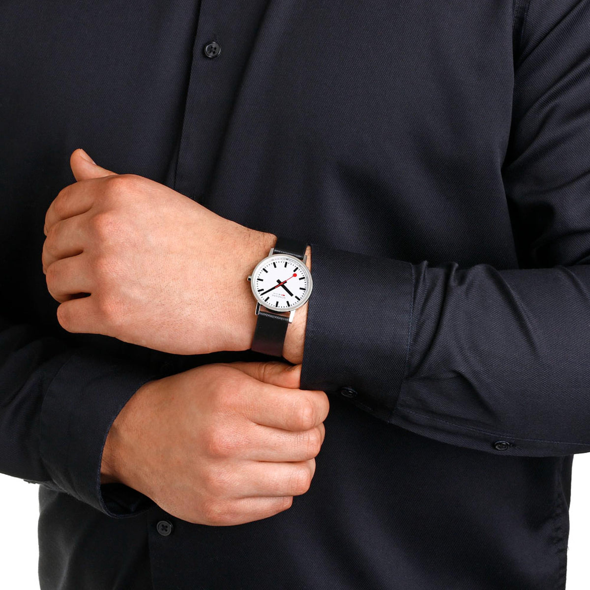 Quartz wristwatch on person’s wrist, white dial with red seconds, black leather band