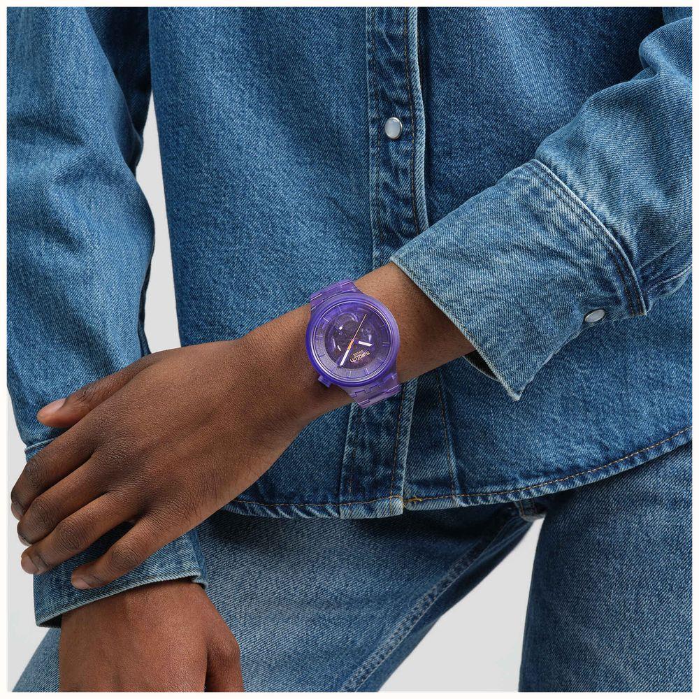 Purple Swatch strap watch worn with denim jacket; round dial and textured band