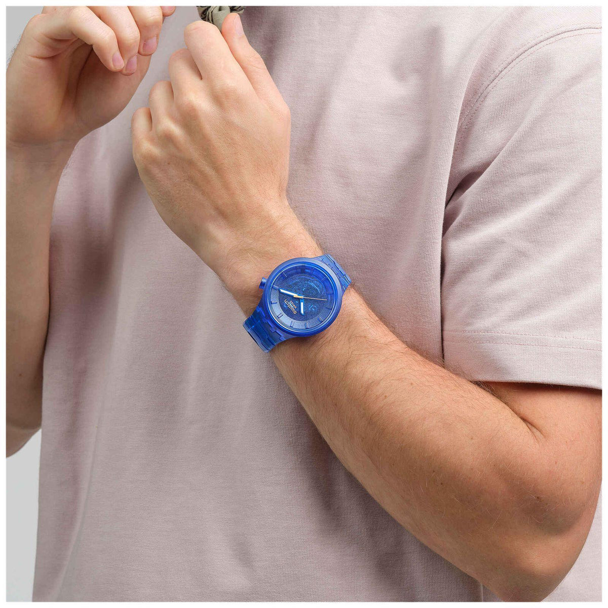 Swatch blue dial watch on wrist, blue bio-based strap and orange seconds hand