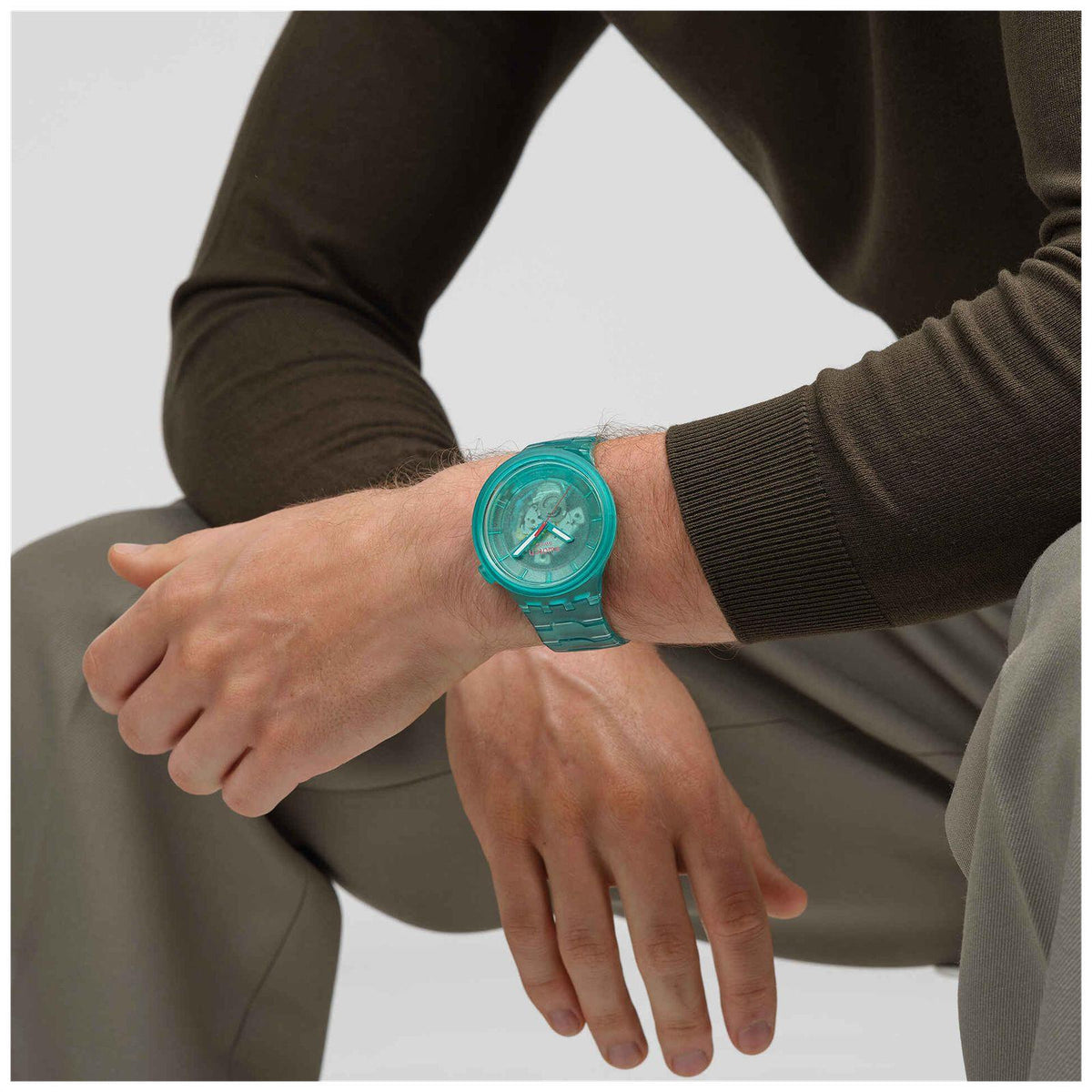 Turquoise clear-case wristwatch on wrist, three-hand dial