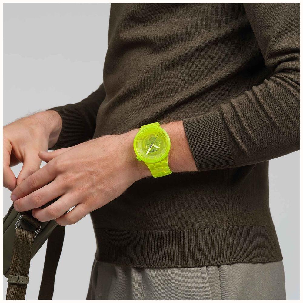 Neon yellow Swatch Joy wristwatch on wrist, round yellow dial with translucent strap