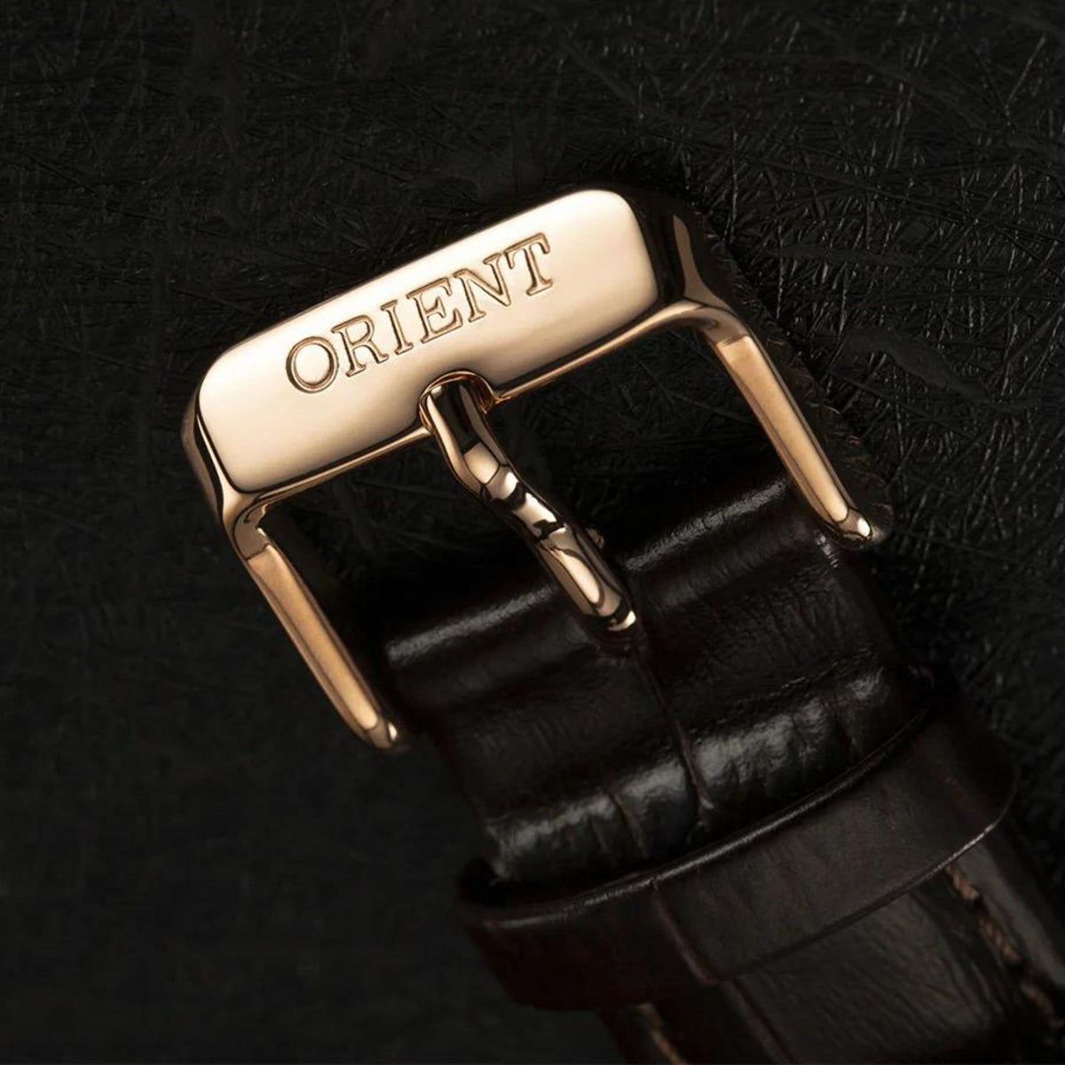 Brown leather watch strap with metal buckle showing ORIENT logo, gold-tone hardware