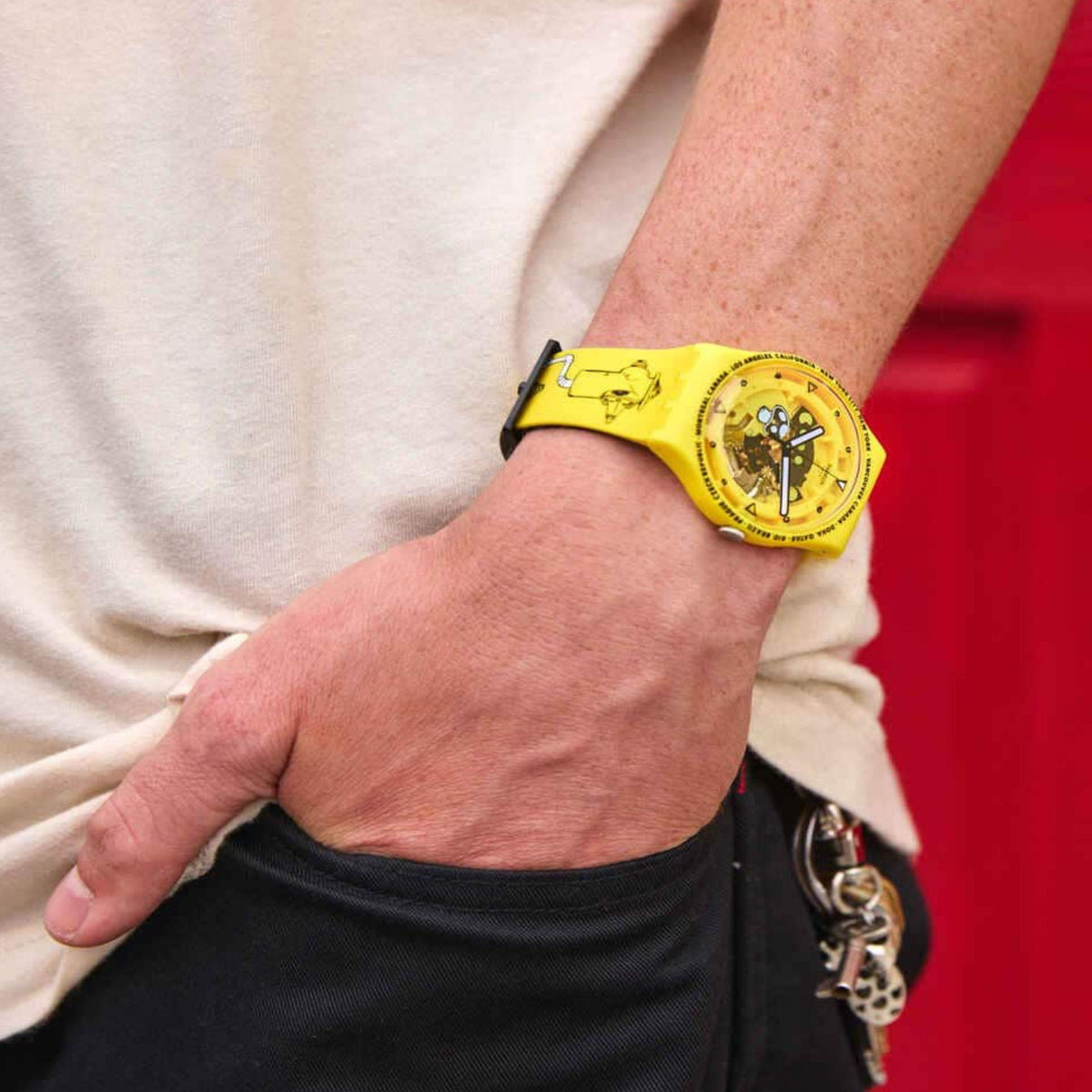 Yellow silicone Swatch watch with black graphic dial on a wrist