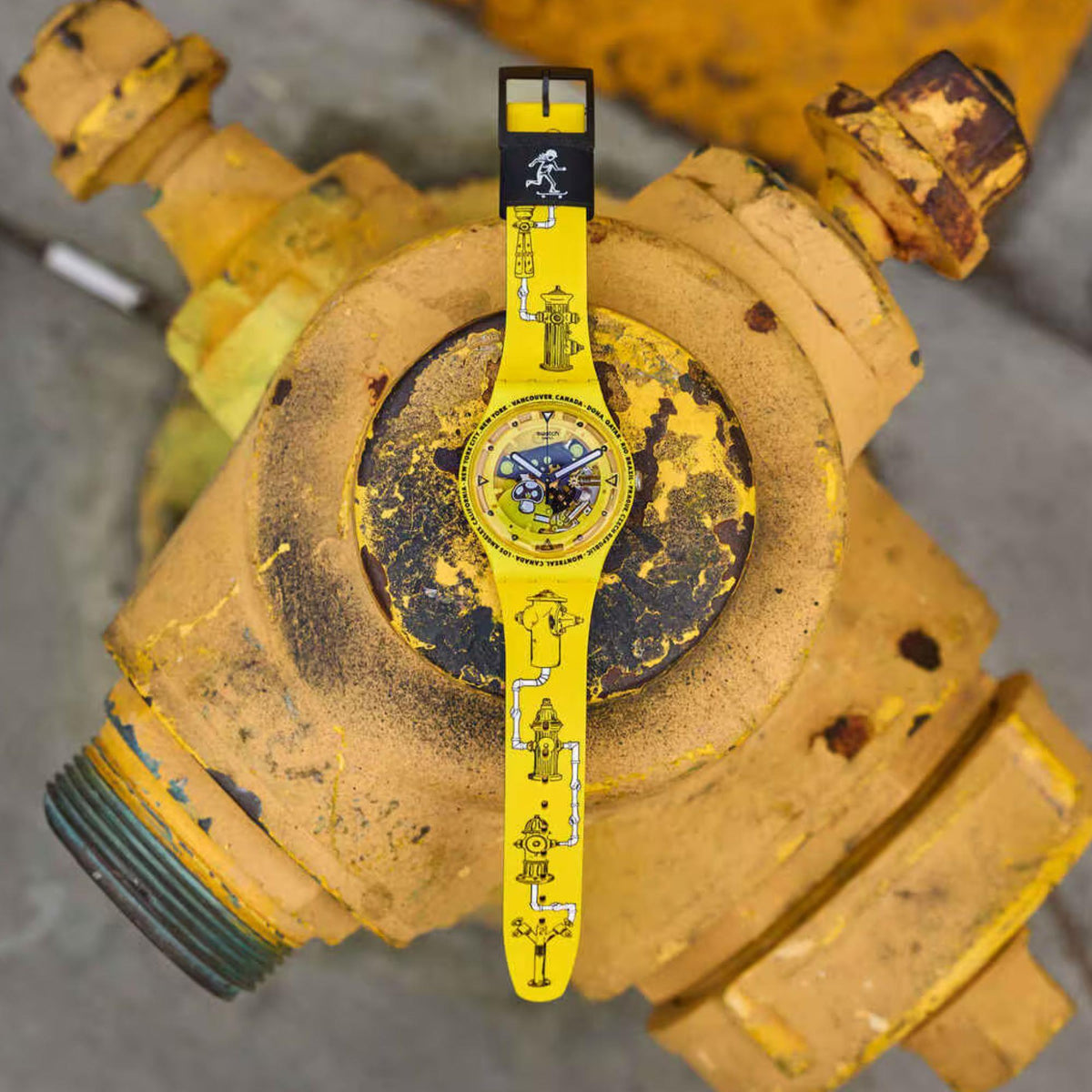 Yellow silicone Swatch watch with black dial on a textured, weathered surface